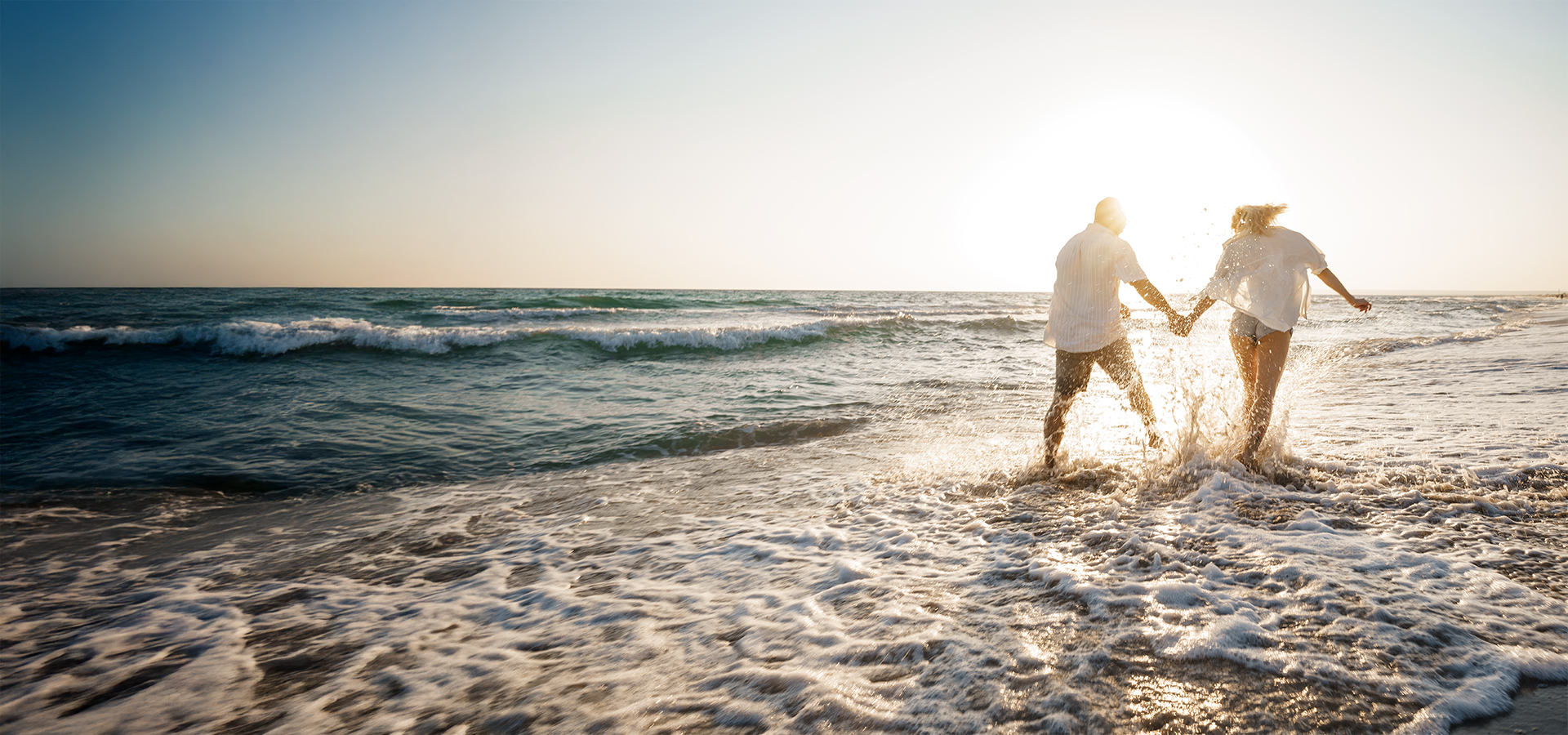 Couple walking on beach at sunset representing longevity and prevention